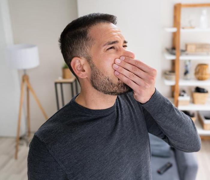 A man holding his nose after smelling a bad odor in his home